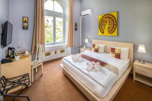 a bedroom with a large white bed with a window at Andrassy Thai Hotel in Budapest