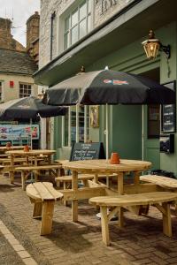 柯比斯蒂芬The Pennine Inn的一组野餐桌,在建筑前摆放着雨伞