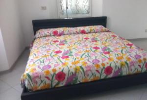 a bed with a floral comforter on top of it at casa Andreea in Domodossola