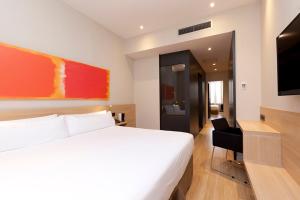 a hotel room with a white bed and a flat screen tv at Hotel Àmbit Barcelona in Barcelona