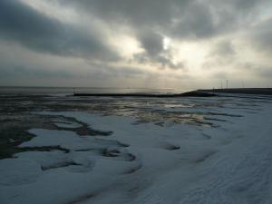 a body of water with snow on the beach at Apartment Korthals 42 in Wangerland +3 photos