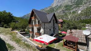 a house with a red umbrella in front of it at Stonehouse villa in Valbonë