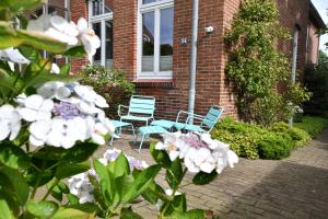 two blue chairs and flowers in front of a brick building at Gaestehaus-St-Josef-9 in Borkum +6 photos