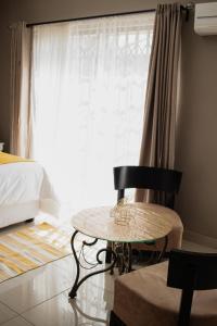 a bedroom with a table and a bed and a window at If Not Why Not Guesthouse in Potchefstroom