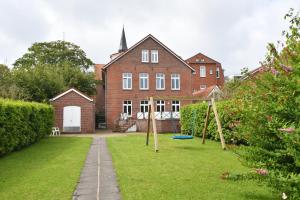 a house with a yard with swings in front of it at Gaestehaus-St-Josef-5 in Borkum +8 photos