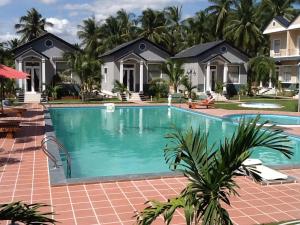 a pool in front of a house with palm trees at Areca Resort in Mui Ne