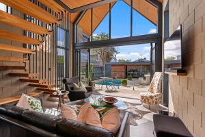 sala de estar con sofá de cuero y ventanas grandes en Divine on Derby - Christchurch Holiday Home, en Christchurch