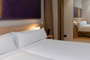 a white bed in a hotel room with two beds at Hotel Àmbit Barcelona in Barcelona