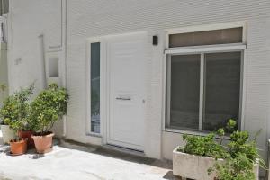 a white door on the side of a house with plants at Chora's Stonehouse in Andros