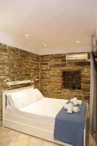 a bedroom with a white bed and a brick wall at Chora's Stonehouse in Andros