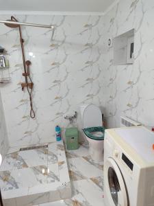 a bathroom with a toilet and a washing machine at Bayel Guest house in Kochkorka