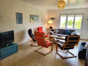 a living room with chairs and a couch and a tv at Maison de bord de mer, les Fleurs in Créances