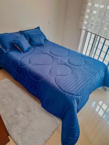 Una cama con un edredón azul en un dormitorio. en Apartamento Duplex en ubicacion privilegiada, en Manizales