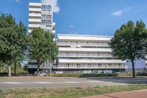 a large white building with trees in front of it at Modern appartement met gratis fietsen in Breda