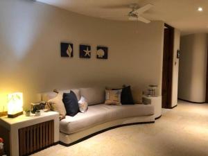 a living room with a white couch with pillows at Hermosa villa a pie de playa in Barra de Potosi