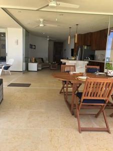a living room with a wooden table and a kitchen at Hermosa villa a pie de playa in Barra de Potosi +9 photos