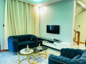 a living room with two blue couches and a tv at Triple s homes in Arusha