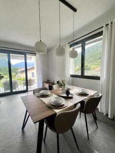 a dining room with a table and chairs and windows at NaLia Apartment in Ossuccio in Ossuccio