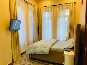 a bedroom with a bed with a tv and windows at Triple s homes in Arusha
