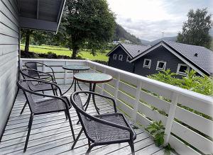 four chairs and tables on a deck with a fence at Selje Camping - Hytte Nr 4 in Selje