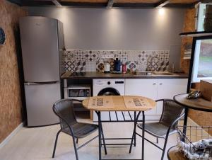 a kitchen with a table and chairs and a refrigerator at Studio Cosy Boxes Chevaux en sus in Agnez-lès-Duisans