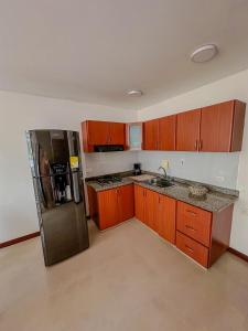 Una cocina con gabinetes de madera y un refrigerador de acero inoxidable. en Apartamento Duplex en ubicacion privilegiada, en Manizales 8 fotos más