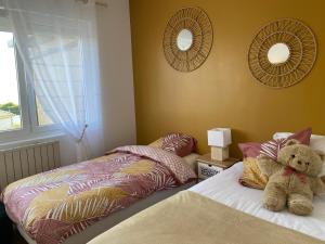 ル・ポルテルにあるLa petite Margotの寝室のベッドの上に座っているテディベア