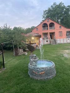 a bird standing on a fountain in front of a house at Guest house and cellar MAMULI in Tʼerjola