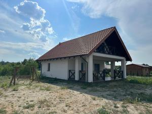 una pequeña casa blanca con techo marrón en Lazurowa Chata Rydzewo, en Rydzewo