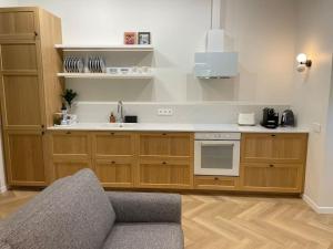 a kitchen with wooden cabinets and a couch in a room at Šilutė's home in Šilutė +33 photos