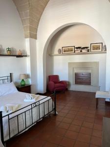 a bedroom with a bed and a chair and a fireplace at B&B Palazzo Giordano Luxury Rooms in Squinzano