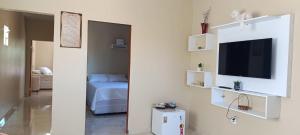 a room with a bed and a tv on a wall at Pousada Apartamento Flor de Pitaya in Viçosa do Ceará