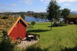 Eine rote Scheune mit Tisch und Stühlen neben einem See in der Unterkunft Åkviktunet hytte nord in Averoy