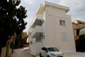 a white building with a car parked next to it at Vila Jovani - Modern Studios with Free Parking, Quiet Area,8 min Walk to Beach in Sarandë