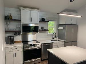 a kitchen with white cabinets and stainless steel appliances at Couples Getaway-Dual-Head Shower for Two in Sautee Nacoochee