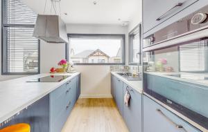 a kitchen with blue cabinets and a large window at Maison Moderne Proche Plage in Saint-Coulomb