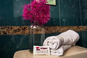 a bathroom with a vase with pink flowers and towels at Casa del Arupo B&B in Quito +46 photos