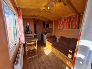 a tiny house with a couch and a table in it at stop roulotte in Burthecourt-aux-Chênes