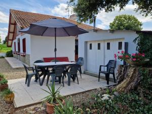 a patio with a table and chairs and an umbrella at Maison du Coucou in Larbey