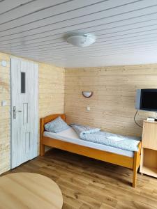 a small room with a bed and a tv at Pokoje&Domki w Pobierowie in Pobierowo