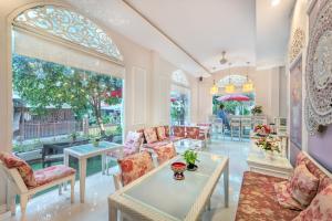 a living room with chairs and tables and windows at SHIN Hotel Chiangmai Gate in Chiang Mai
