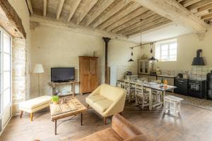 a living room with a table and a kitchen at Chez Marguerite et Bienaimé in Picauville
