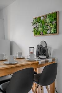 einen Tisch mit zwei Stühlen und ein Blumengemälde an der Wand in der Unterkunft Le Jardin Secret in Seyssinet-Pariset