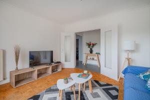 ein Wohnzimmer mit einem blauen Sofa und einem Fernseher in der Unterkunft Le Jardin Secret in Seyssinet-Pariset