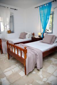 2 letti in una camera da letto con tende blu di Anezo's Exceptional View a Spetses