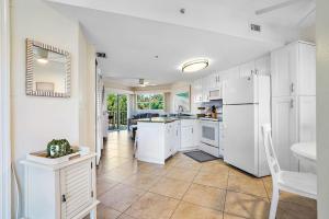 a kitchen with white cabinets and a white refrigerator at Sunrise Resort 210 in St Pete Beach