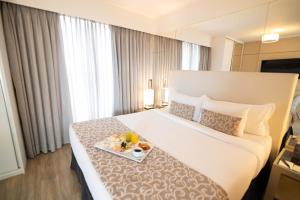 a hotel room with a bed with a tray of food on it at H2 Platinum Lourdes in Belo Horizonte