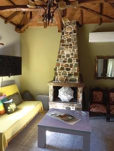 a living room with a couch and a stone fireplace at Stone and Serenity Cottage in Pilion