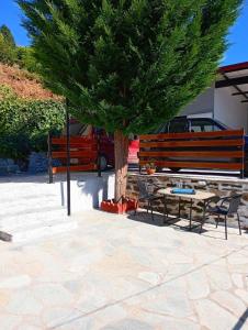 a table and chairs under a tree next to a bench at Stone and Serenity Cottage in Pilion