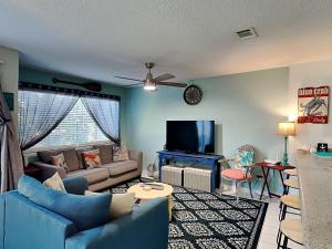 Una sala de estar con un sofá azul y un televisor. en Island Home 102, en Destin